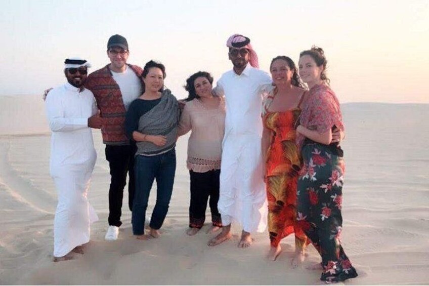 A group of people standing on a sandy beach with a clear sky. 5