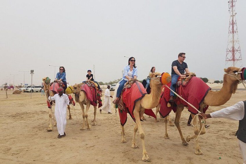 A group of people riding camels in a desert setting. 2