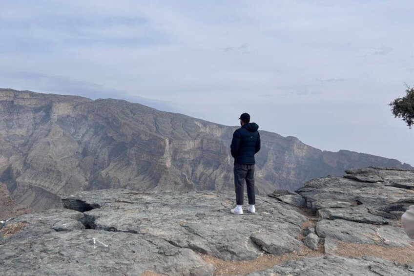 A person standing on rocky terrain overlooking a mountainous landscape. 2