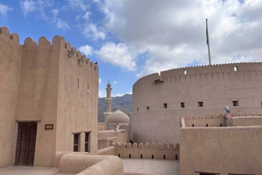 A historic fort with a minaret and a mosque in the background. 5