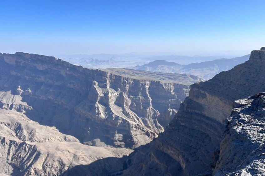 A vast canyon with layered rock formations and a clear blue sky. 3