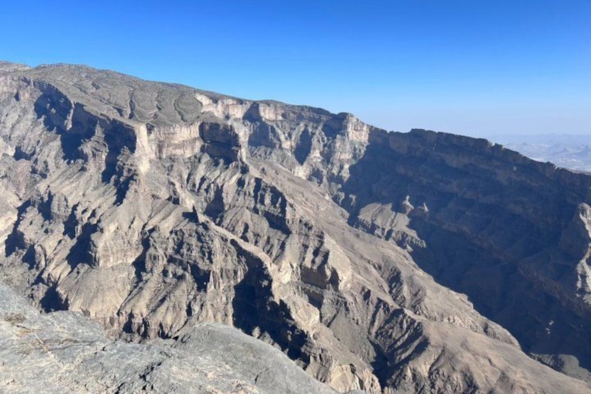 A rugged mountain landscape with layered rock formations and a clear blue sky. 1