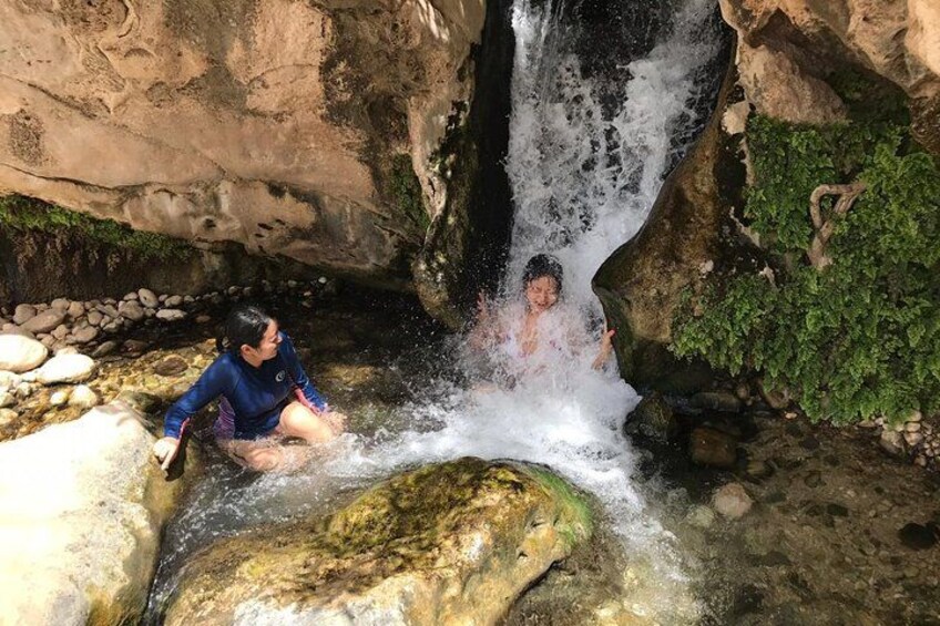 Two people sitting by a waterfall in a rocky cave. 2