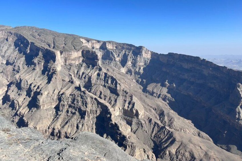 A rugged mountain landscape with layered rock formations and a clear blue sky. 2