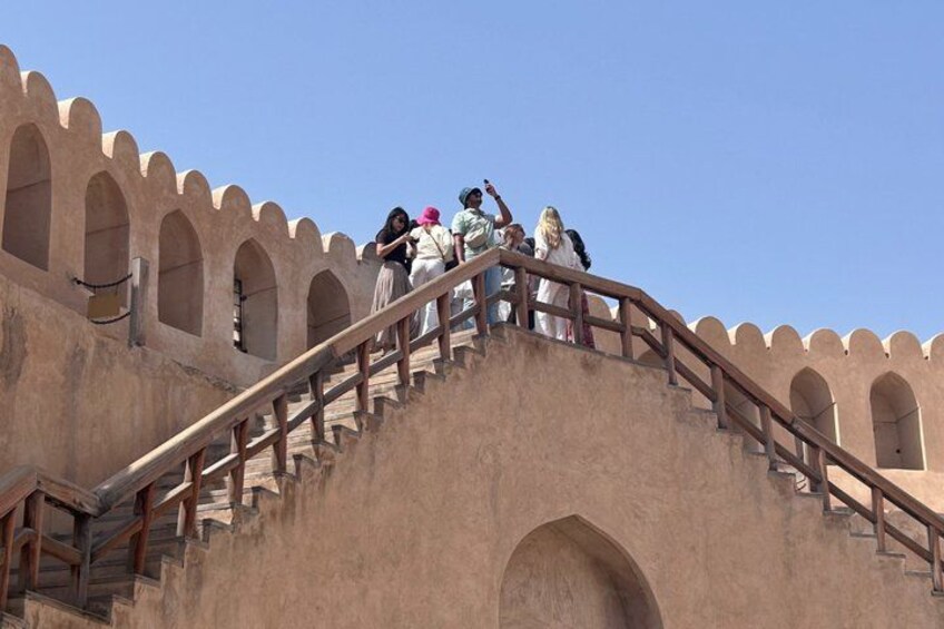 A group of people on a stone staircase with arches, leading to a building with a flat roof. 5