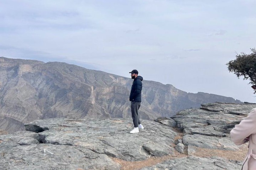 A person standing on rocky terrain with a mountainous backdrop. 3