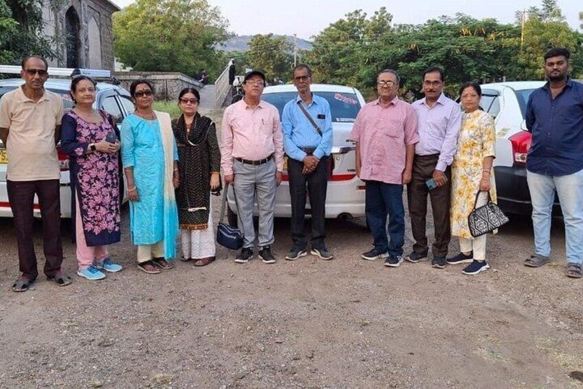 A group of people standing in a line with cars parked behind them. 5