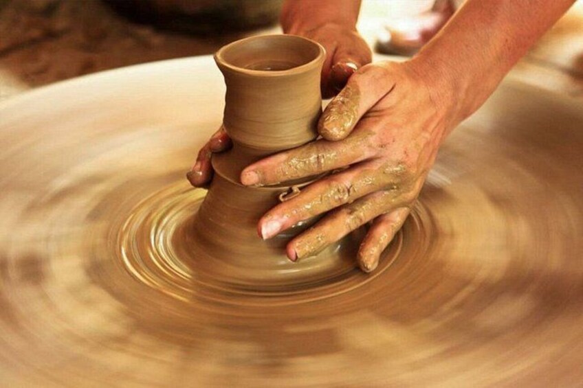 Hands shaping a clay pot on a spinning wheel. 4