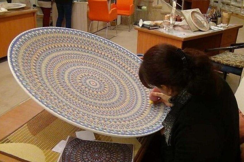 A person sitting at a table with a large, intricately patterned plate. 5