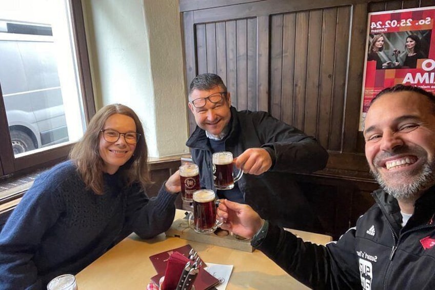 Tres personas brindando con vasos de cerveza en una mesa de madera en un restaurante. 5