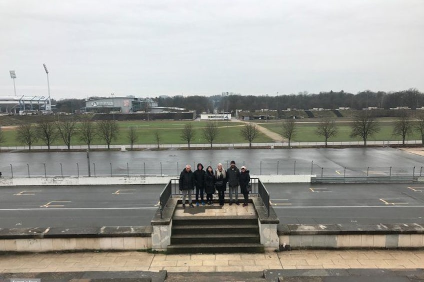 A group of people standing on a set of stairs overlooking a sports field. 4