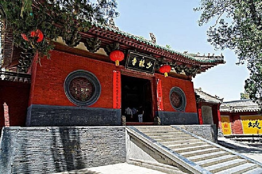 A traditional Chinese building with red walls, a tiled roof, and a staircase leading up to the entrance. 3