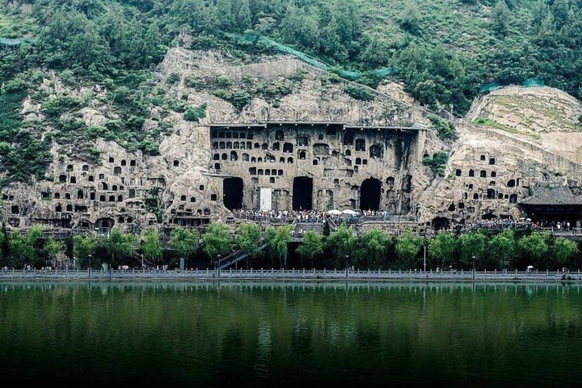 A historical rock-cut architecture with multiple levels and a reflection in the water. 1