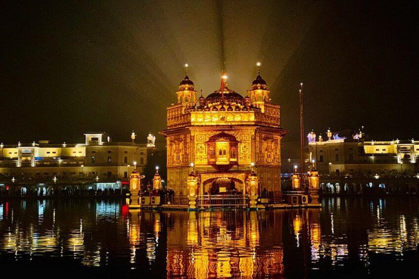 A brightly lit temple at night with reflections on water. 2