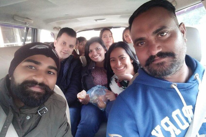 A group of people inside a vehicle, possibly a bus or van, with seats and windows visible. 5