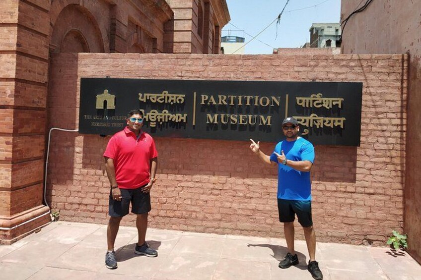 Two people standing in front of a sign for the Partition Museum. 3