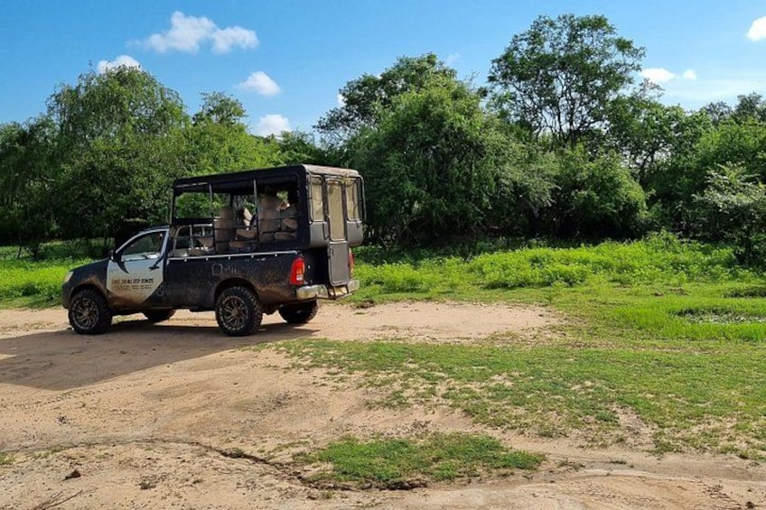 A black SUV on a dirt road with greenery and trees in the background. 2