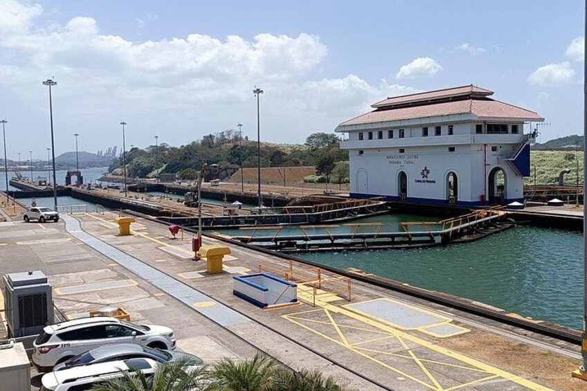 A harbor with a white building, a road with cars, and a body of water. 3