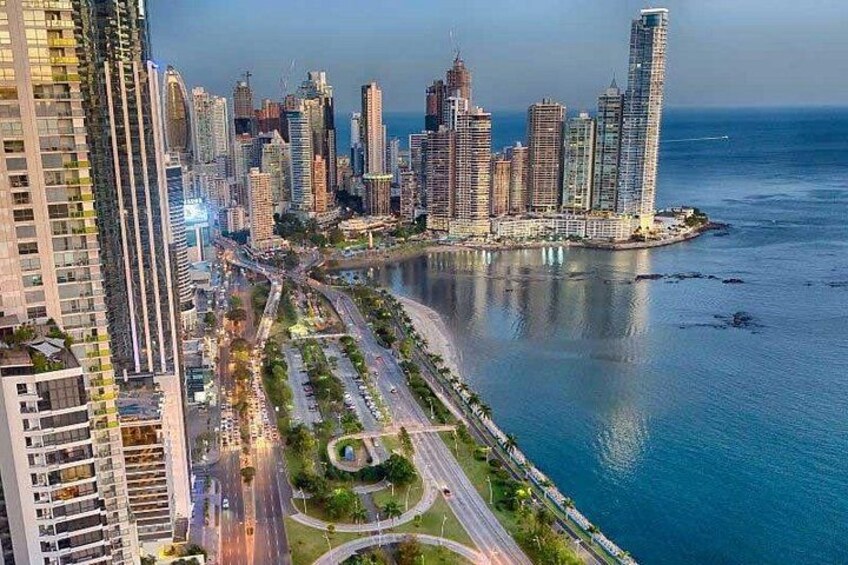 A coastal cityscape with high-rise buildings, a marina, and a curved road leading to the water. 4