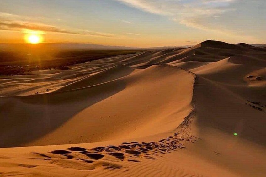 A desert landscape with sand dunes and a setting sun. 4