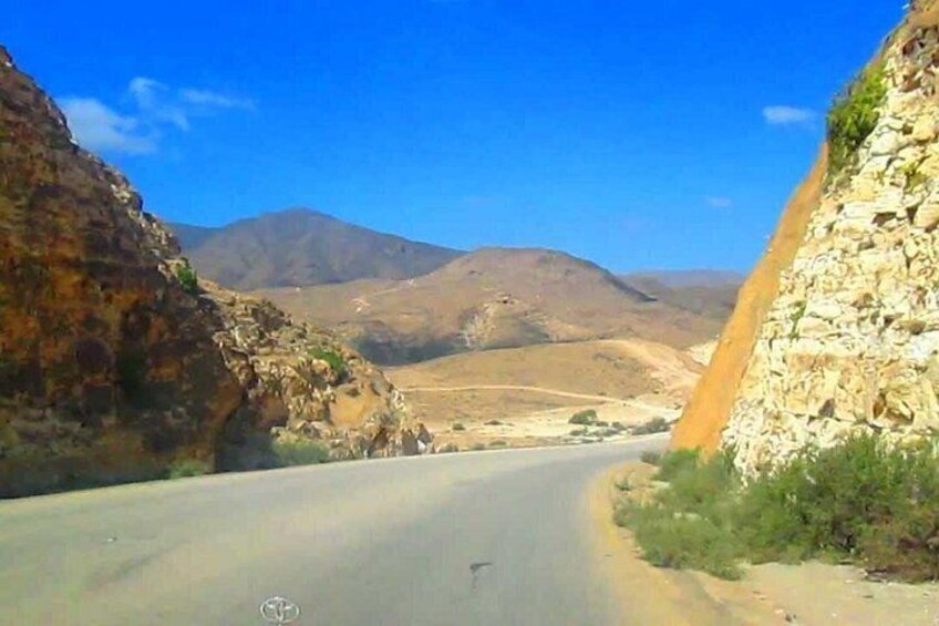 A road through a mountainous area with rocky cliffs on either side. 4