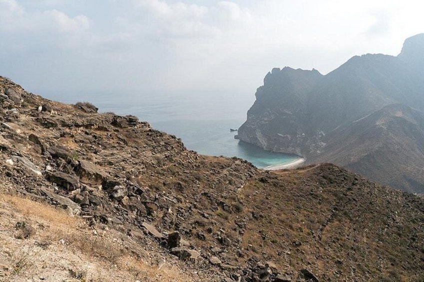 A rugged mountainous landscape with a rocky terrain and a beach in the distance. 5