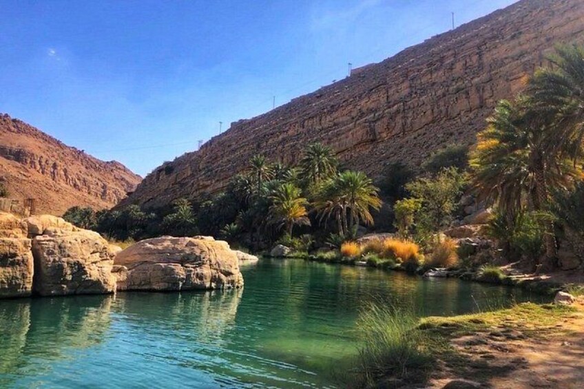 Un fiume con acque limpide, circondato da colline rocciose e palme. 3