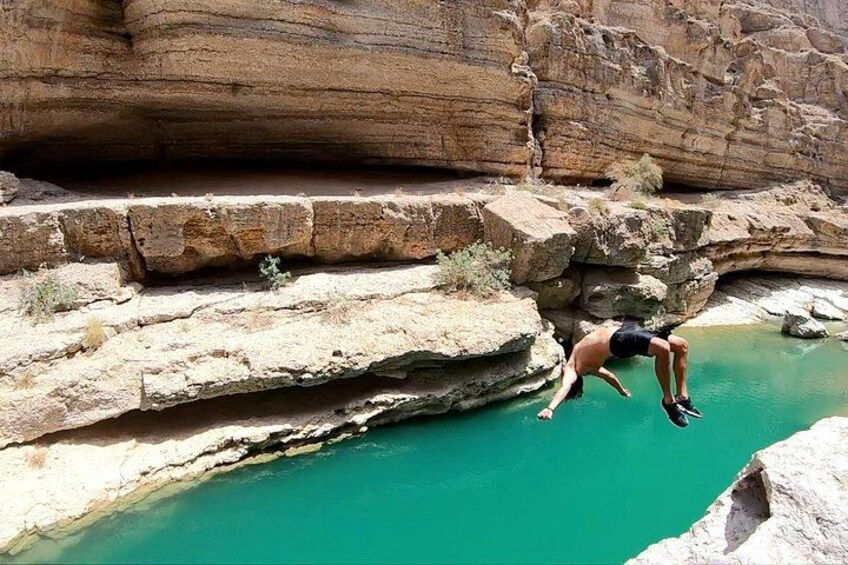 A person jumping off a cliff into a turquoise pool. 2