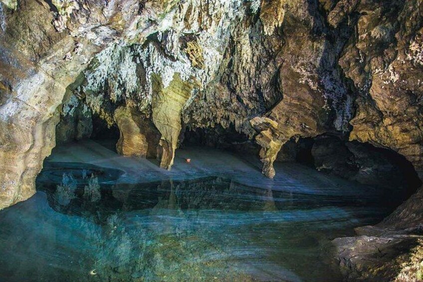 Una grotta con stalattiti e una pozza d'acqua. 5