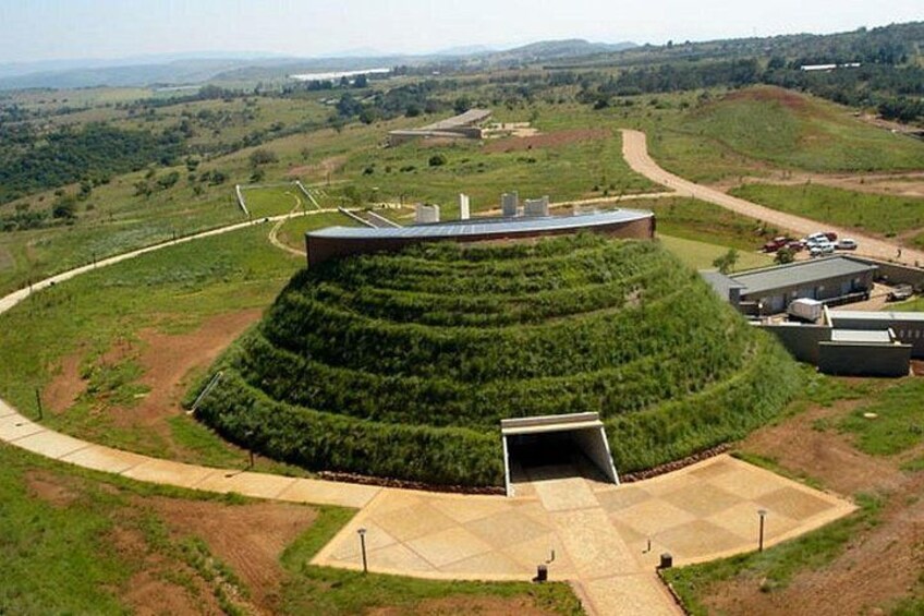 Un grande edificio circolare con tetto piatto, circondato da campi verdi a terrazza. 4