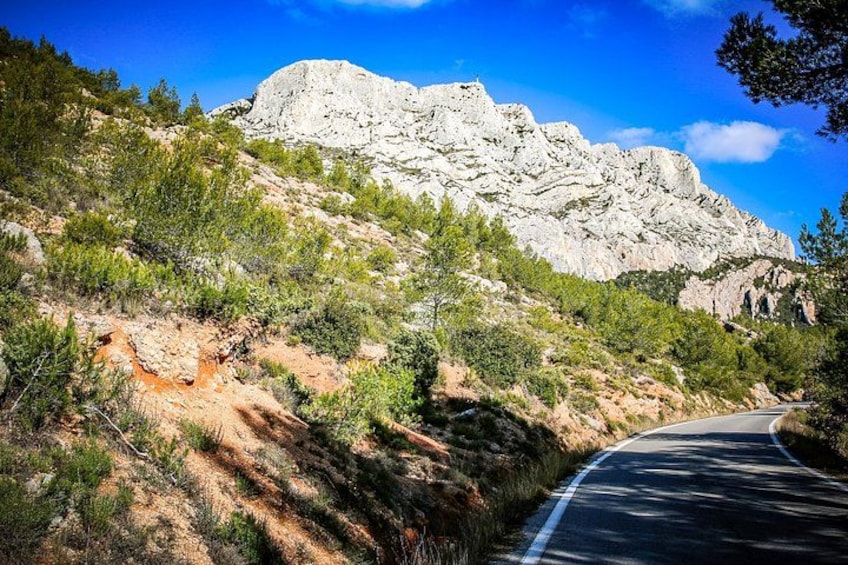 A winding road, rocky terrain, and a prominent mountain in the background. 1