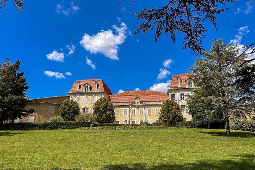 A large building with a red roof, surrounded by a well-maintained lawn and trees. 2