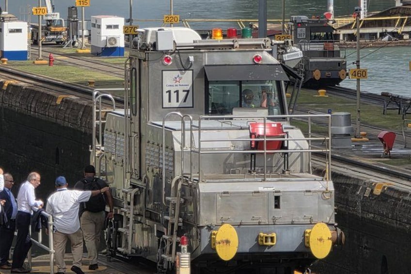Un train portant le numéro 117, entouré de bâtiments industriels et bordé par un plan d’eau. 3