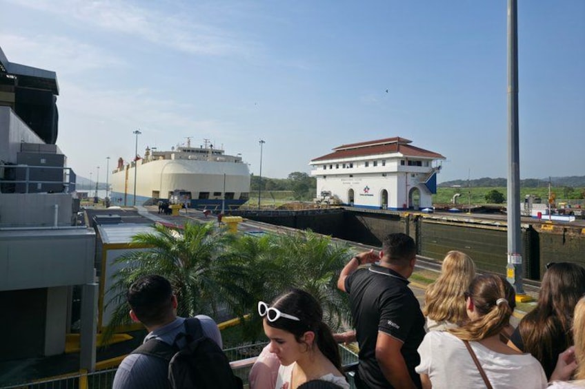 Een groep mensen op een boot, een groot gebouw en een brug op de achtergrond. 4