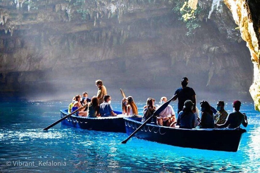 Two rowboats with people on a calm body of water, surrounded by rocky cliffs. 2