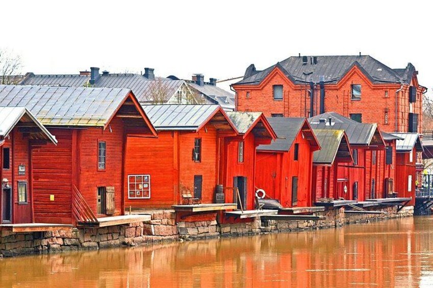 A row of red wooden buildings by a calm water body. 2