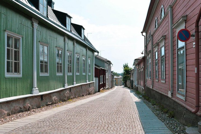 A cobblestone street lined with historic buildings, one painted green and the other red. 5