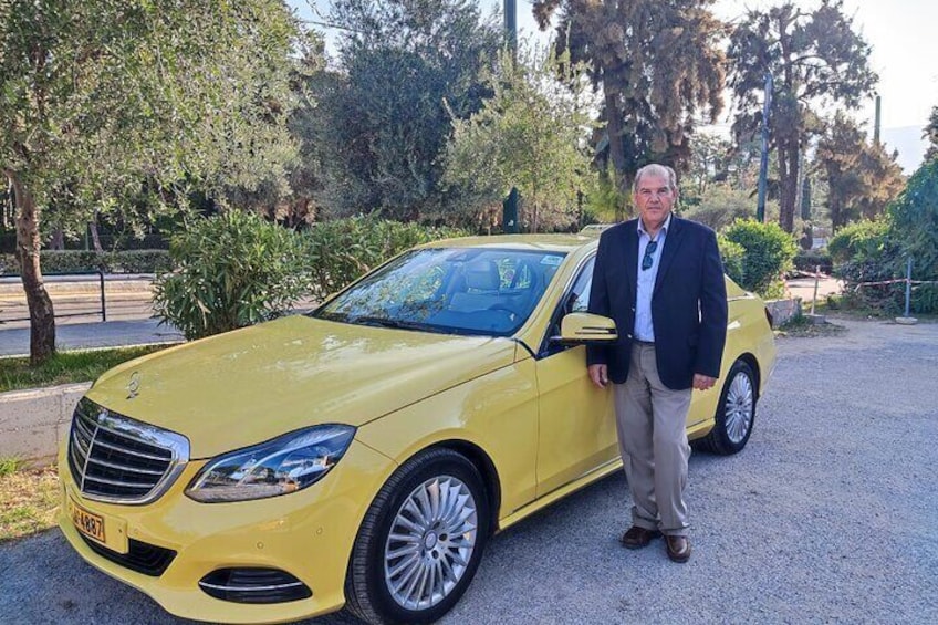 Ein gelber Mercedes-Benz Roadster steht auf einem Schotterweg, im Hintergrund sind Bäume zu sehen. 5