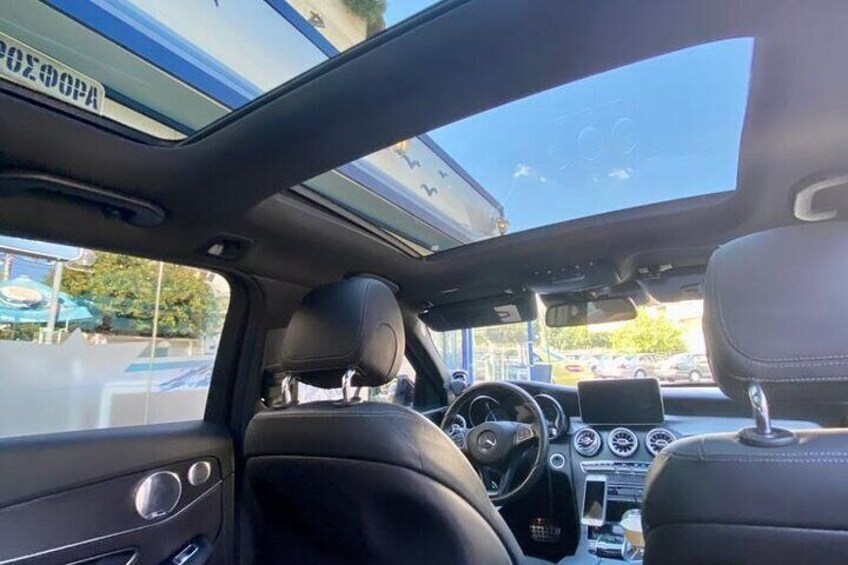 Ein Auto Innenraum mit Panoramadach, Ledersitzen und Armaturenbrett mit Lenkrad. 2
