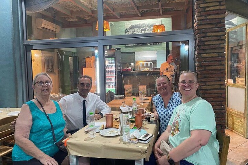 Un grupo de personas sentadas en una mesa dentro de un restaurante, con vista a la cocina a través del ventanal. 3