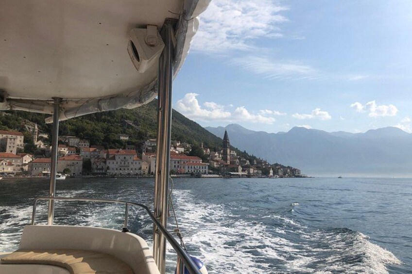 A boat on water with a view of a coastal town and mountains in the background. 2