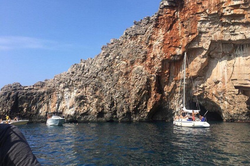 A rocky coastline with a sailboat anchored near the shore. 5