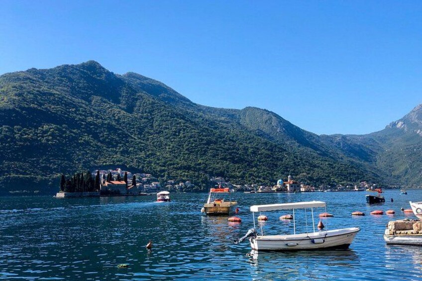 A lake with boats, a small island, and mountains in the background. 4