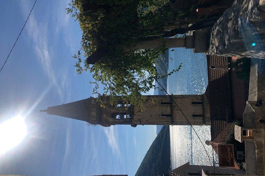 Una torre con la punta appuntita, cielo sereno e un albero con foglie verdi. 1