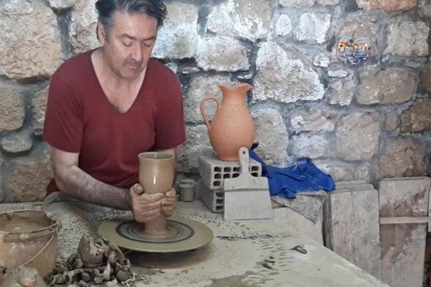 Una persona trabajando en un torno de alfarería, con arcilla y herramientas a la vista. 4