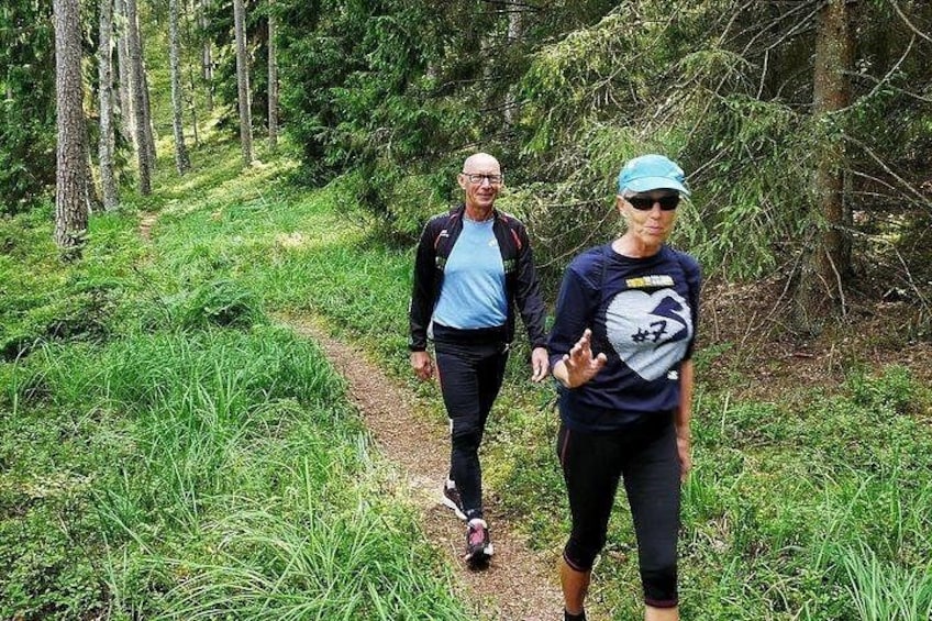 Dos personas caminando por un sendero boscoso, rodeado de follaje. 1