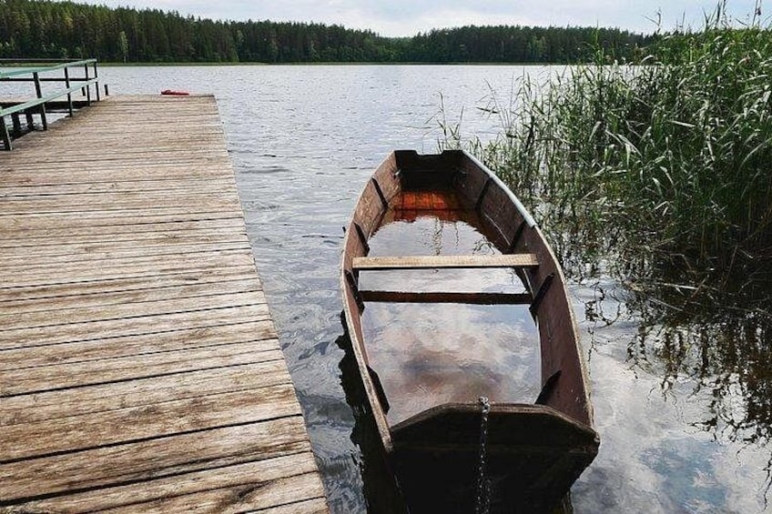 Un bote de madera en un lago tranquilo, amarrado a un muelle de madera con un bosque al fondo. 5