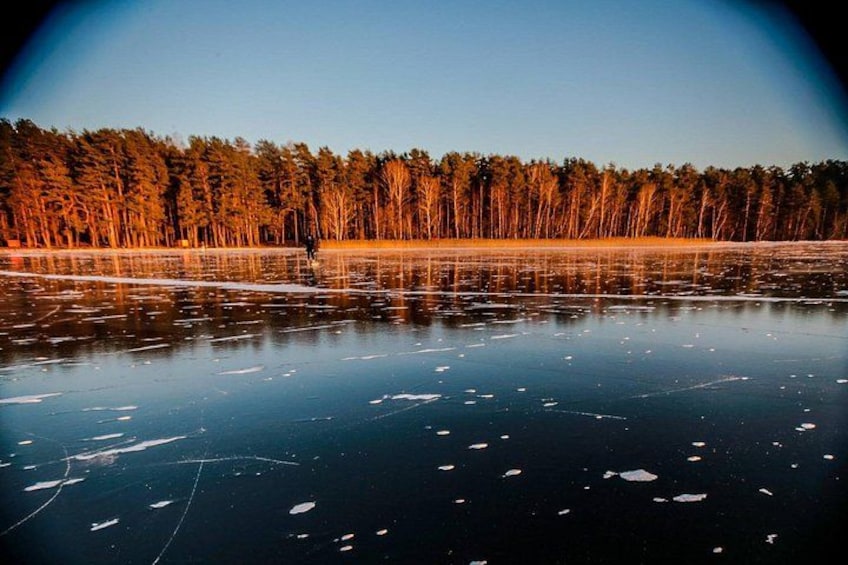 Un lago congelado con reflejos de árboles y un cielo despejado. 2
