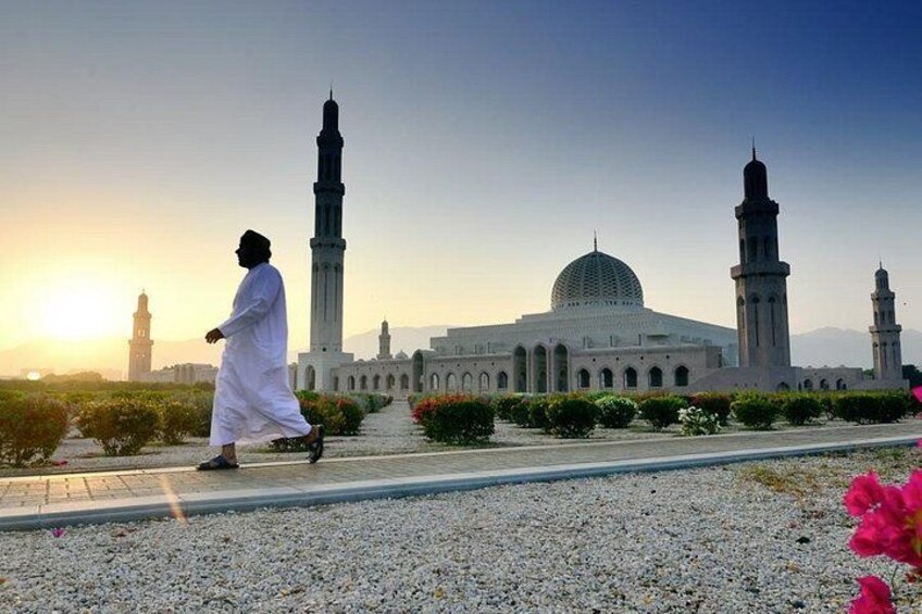 Une personne marchant devant une mosquée dotée d’un dôme et de minarets. 3