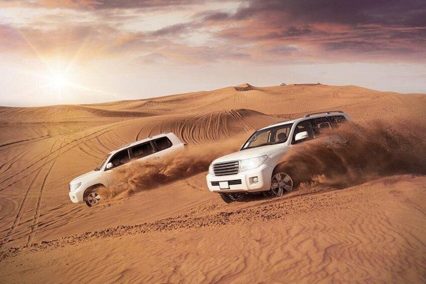Due SUV bianchi fuoristrada in un deserto con dune di sabbia e un tramonto. 3
